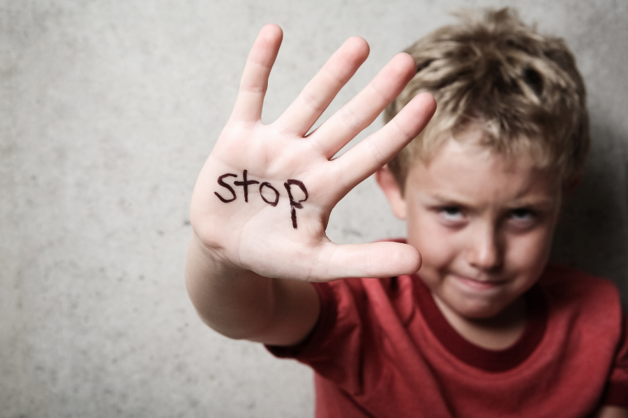 niño con "stop" dibujado en la mano. denunciar maltrato psicológico